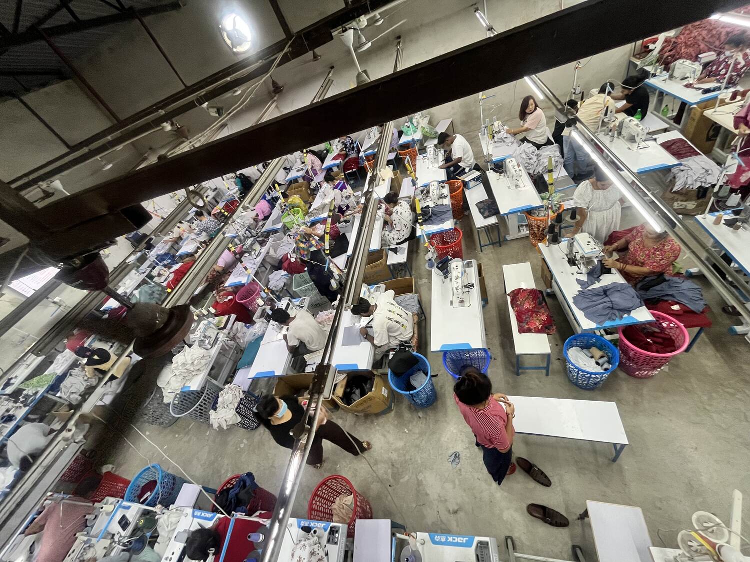 Overhead view of the Trishakti Apparel sewing floor in Gaindakot, Nepal — rows of industrial machines with operators working on knit garments