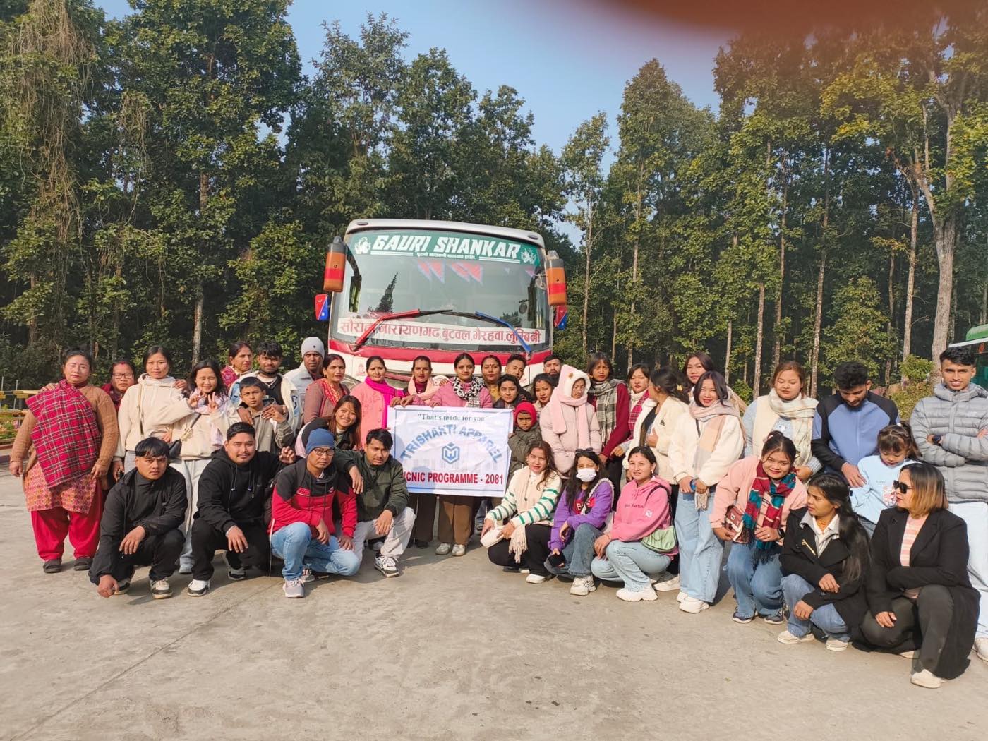 The Trishakti Apparel team photographed with the company picnic banner before boarding the bus