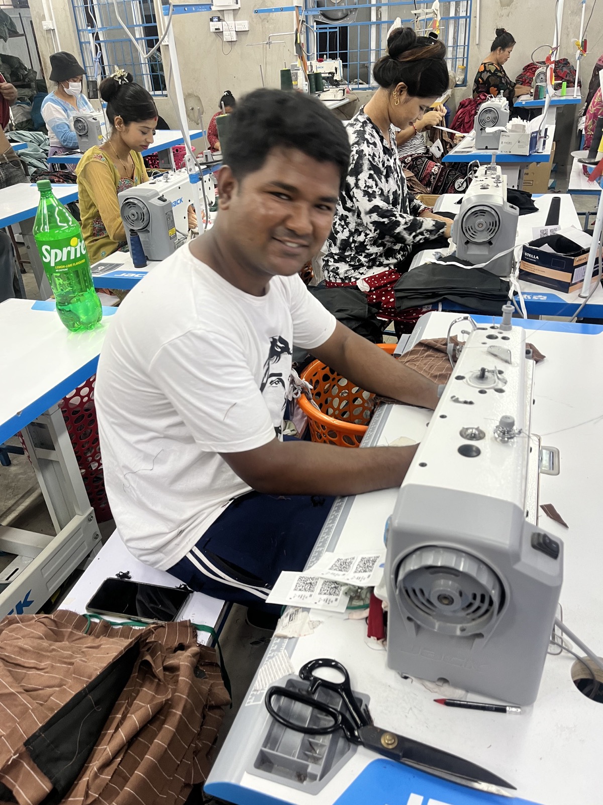 A Trishakti Apparel production operator working at an industrial sewing machine in Gaindakot, Nepal