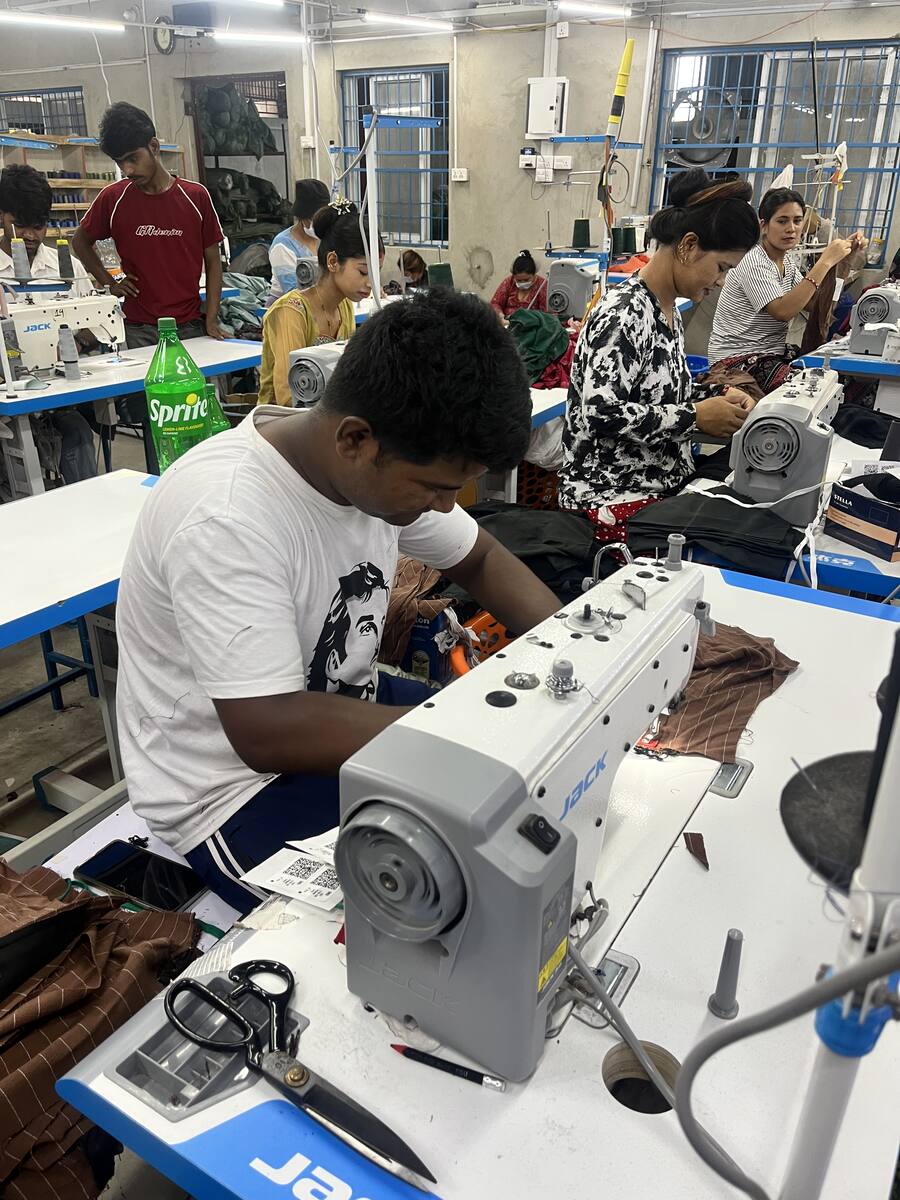 A machine operator sewing at an industrial lockstitch machine on the Trishakti Apparel knit line in Gaindakot, Nepal